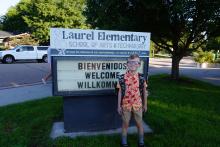 Student posing in front of school sign