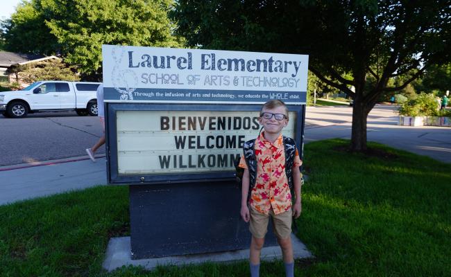 Student posing in front of school sign