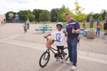 Principal Garcia posing with a second grader and his new bike